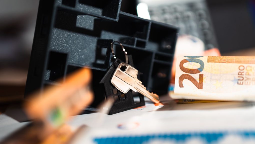 Keys with a house model, Euro bills, and charts suggesting real estate and financial themes.