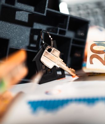 Keys with a house model, Euro bills, and charts suggesting real estate and financial themes.