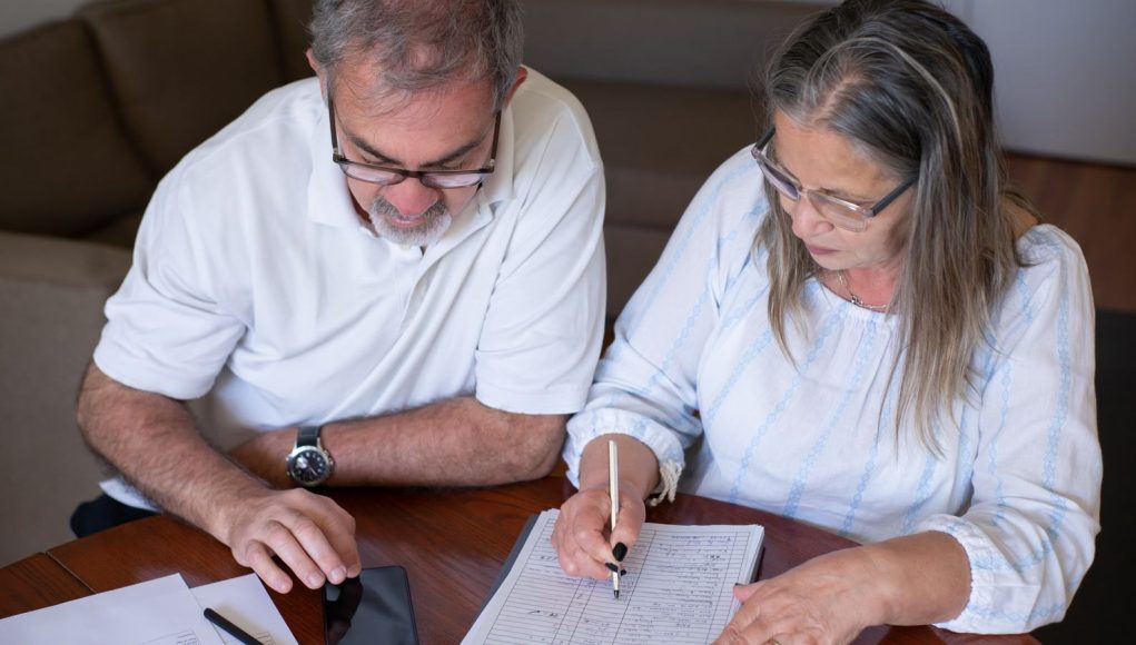 Before taking tax-free pension cash, consider the problems it can create later: an older couple going through pension and retirement paperwork together at home