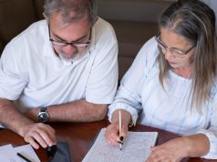 Before taking tax-free pension cash, consider the problems it can create later: an older couple going through pension and retirement paperwork together at home