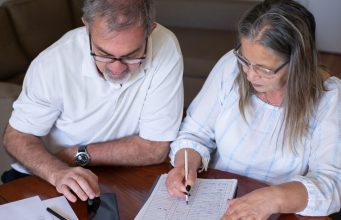 Before taking tax-free pension cash, consider the problems it can create later: an older couple going through pension and retirement paperwork together at home