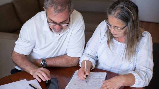 Before taking tax-free pension cash, consider the problems it can create later: an older couple going through pension and retirement paperwork together at home