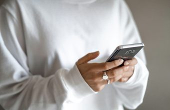 Budget limits, waiting periods and planned repayments can curb stress-driven spending: a person in a white jumper checking their household budget on a mobile phone