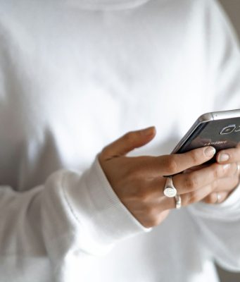 Budget limits, waiting periods and planned repayments can curb stress-driven spending Budget limits, waiting periods and planned repayments can curb stress-driven spending: a person in a white jumper checking their household budget on a mobile phone
